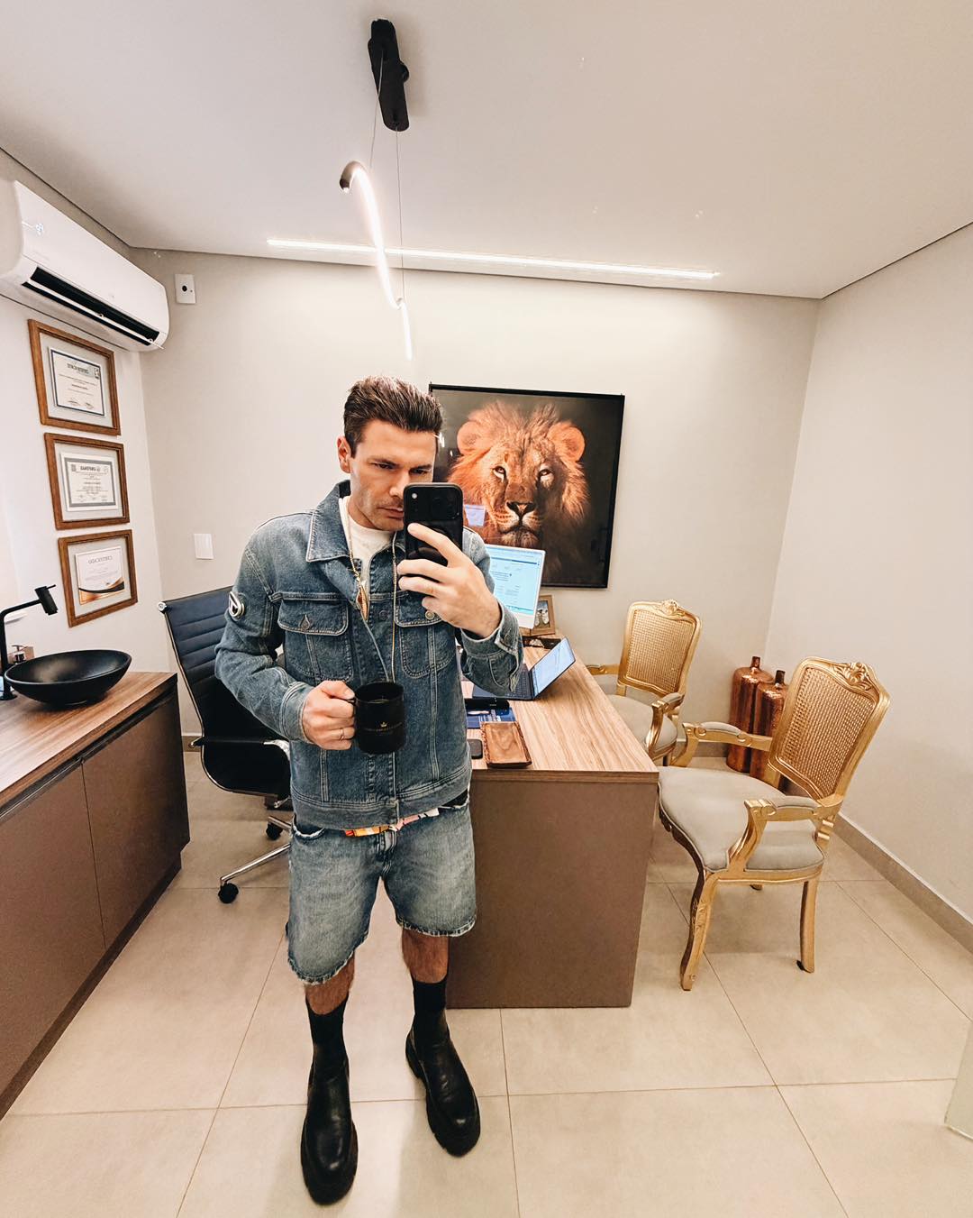 Dr. Thomaz Cortez em uma fotografia pessoal no espelho do consultório, com uma caneca na mão.